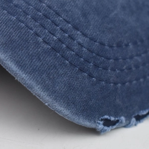 Close-up of distressed brim on navy washed denim baseball cap with reinforced stitching