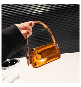 Close-up of metallic gold patent leather handbag with glossy mirror finish and strap