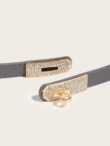 Detailed macro view of the grey cross-grain leather belt with a gold crystal-encrusted buckle