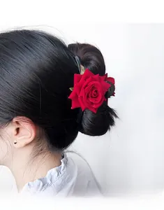 Detail of elegant deep red rose hair claw clip with green leaves worn on hair