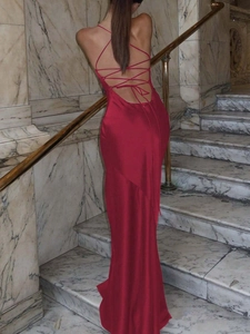 Elegant red backless satin dress with lace-up straps on a marble staircase setting