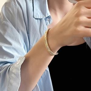 Detail showing two-tone gold and silver plated bangle with textured surface on model
