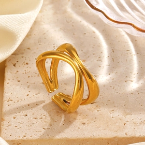 Anello incrociato minimalista in acciaio inossidabile dorato su superficie in pietra