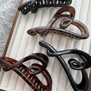 Elegant matte black and tortoiseshell heart hair claws for women displayed on velvet tray