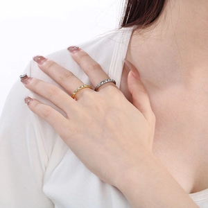 Close-up of model wearing gold and silver stainless steel rings with sparkling inlaid diamonds