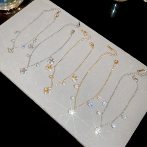 Detailed view of zircon star and cross charms on adjustable gold and silver bracelets