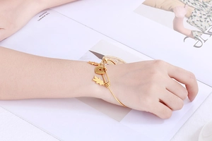 Detail view of a gold titanium adjustable heart bracelet worn by a model on a magazine