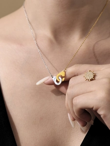 Gros plan du collier menottes bicolore or et argent avec une bague en diamant brillant