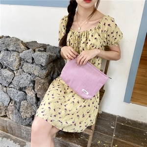 Macro shot of purple corduroy clutch bag texture against a floral dress and stone background