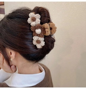 Knitted flower hair claw clip in beige and brown shown on a back bun hairstyle