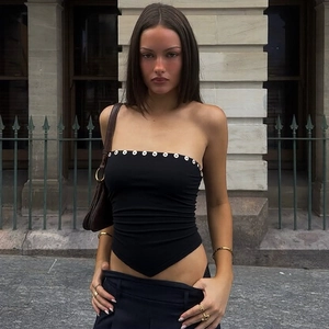 Détail d'un haut bustier noir avec œillets métalliques et ourlet asymétrique en pointe