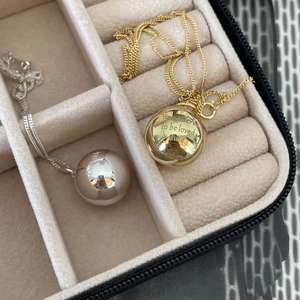 Detailed macro view of gold and silver sphere necklaces with engraved inspirational quotes