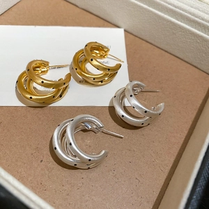 Dettaglio macro di orecchini a C a tre strati in oro e argento spazzolato con pois