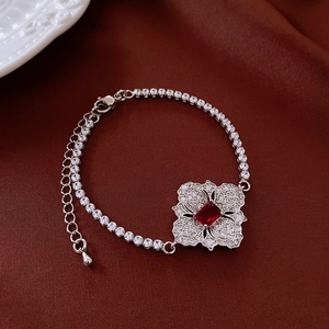 Macro view of silver floral necklace with red square gemstone and white zircon stones