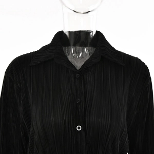 Detail of black pleated texture shirt showing the neckline and single white button accent