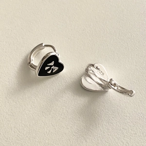 Detailed macro view of S925 silver earrings with black enamel heart and silver bow