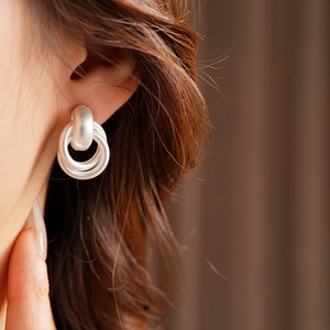 Close-up of a model wearing matte silver interlocking double hoop earrings in retro style