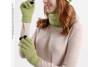 Detail of green knitted beanie, neck warmer and touchscreen gloves set with ribbed texture
