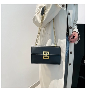 Détail d'un sac bandoulière en cuir noir avec fermoir doré et chaîne sur un mannequin
