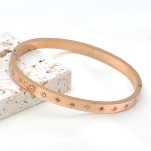 Elegant rose gold stainless steel bangle with engraved star patterns and cubic zirconia stones