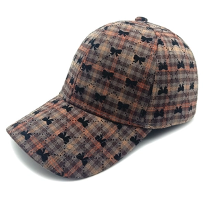Dettaglio cappello da baseball a quadri marroni con motivi di fiocchi neri ricamati