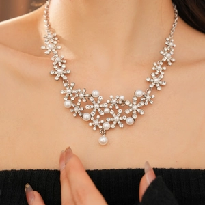 Detail of floral pendant necklace with crystal rhinestones and white pearl on model's neck
