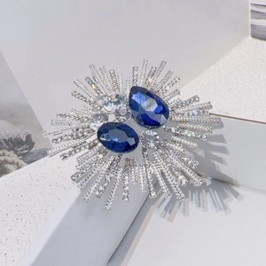 Detailed shot of radial starburst brooch with deep blue gemstones and crystal rhinestones