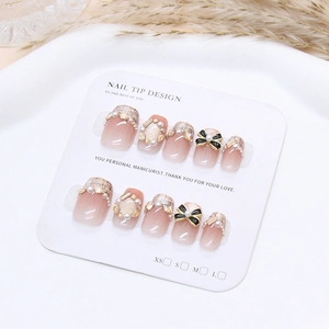 Détail de faux ongles faits main avec effet œil de chat, perles et nœuds élégants