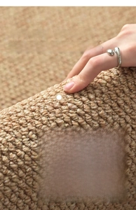 Macro detail of hand-folded woven rug texture showing flexible beige sisal-like material
