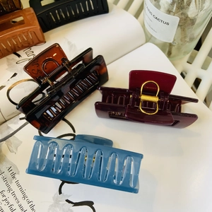 Detail of five large rectangular hair claws in various colors on a fashion magazine background