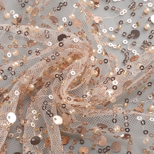 Close-up of rose gold sequins and ivory pearls embroidered on delicate mesh fabric