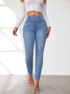 Detail einer hellblauen High-Waist-Jeans mit Distressed-Löchern und fransigen Säumen