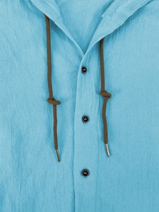 Detail of sky blue linen hooded shirt featuring brown drawstrings and black buttons