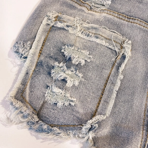Dettaglio di pantaloncini di jeans blu con frange pesanti e cuciture sulla tasca