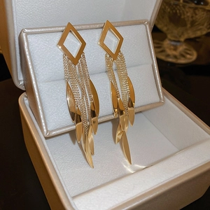 Detail shot of gold tassel flower earrings with pearl accents on a velvet jewelry box