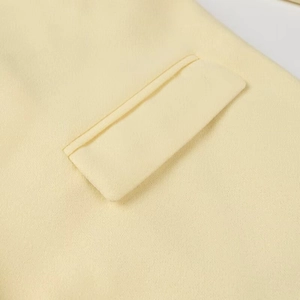 Detail of premium yellow wool coat showing pocket stitching and fine fabric texture