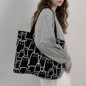 Detail of minimalist black canvas tote bag with white cat line art illustrations