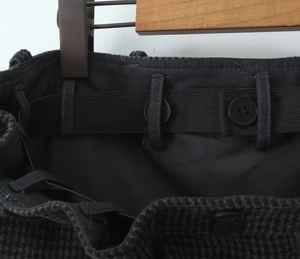 Detail view of the adjustable elastic waistband with buttons on the wool plaid skirt