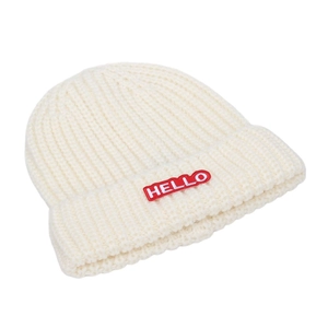 Gros plan du bonnet en maille beige avec texture épaisse et écusson brodé HELLO