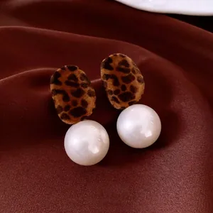 Vintage leopard print flocking earrings with large white pearl drop on silk background