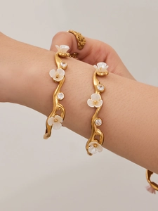 Detail of 18k gold plated stainless steel floral cuff bracelet with white petals and zircon