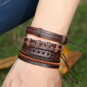 Close-up of stacked vintage brown leather bracelets with braided textures and arrow patterns
