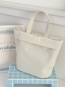 Minimalist cream white tote bag with folded rim design on a blue tiled surface