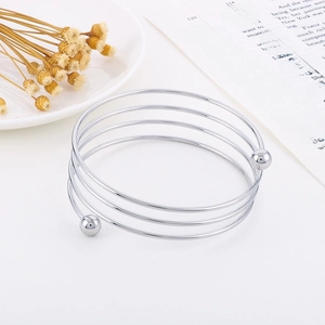 Macro detail of multilayer silver stainless steel spiral bracelet with ball ends on white