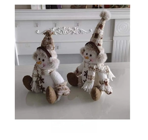 Vue latérale de deux bonhommes de neige en peluche avec bonnets et écharpes tricotés