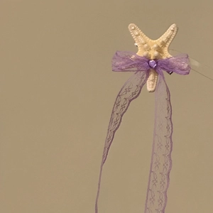 Close-up of a starfish hair clip with a purple lace bow and heart gem detail.