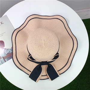 Detail of wide brim straw hat with wavy black edging and large elegant bow decoration