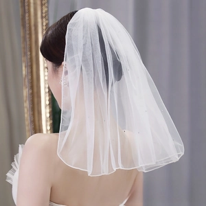 Detailed close-up of short white wedding veil with sparkling rhinestones and soft mesh fabric