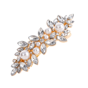 Detail of gold hair clip with sparkling rhinestones and white pearls in leaf design