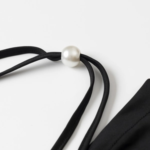 Close-up of black spaghetti straps with elegant white pearl sliding buckle detail